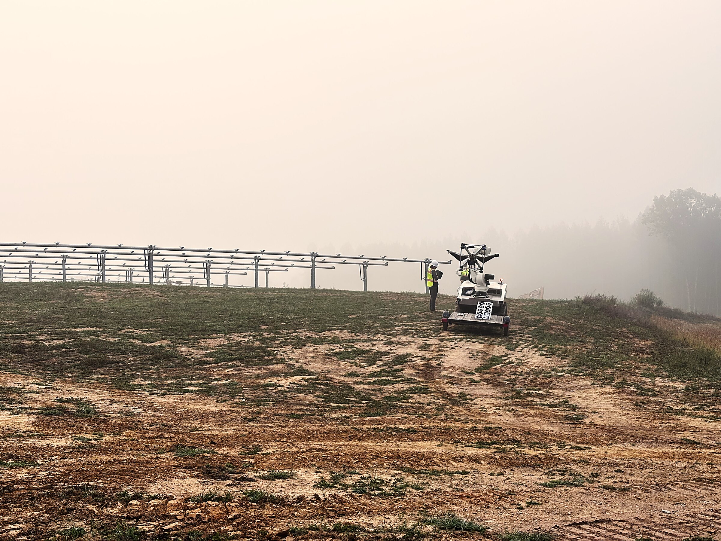 A Cosmic Robotics autonomous platform and technician on a solar construction site at dawn