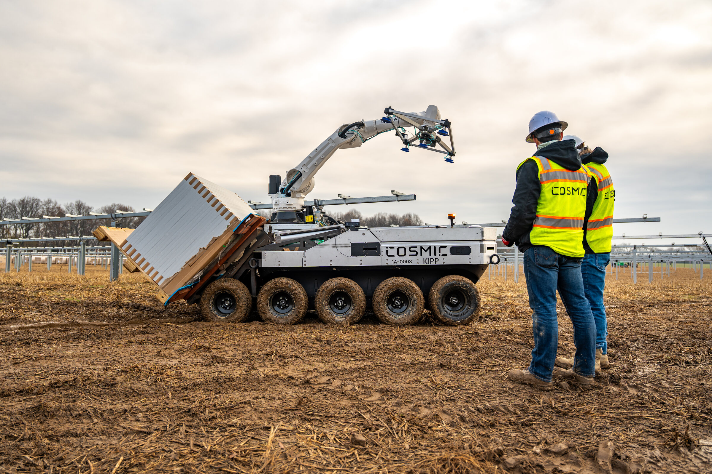 A Cosmic Robotics technician working alongside an autonomous robot in a solar field